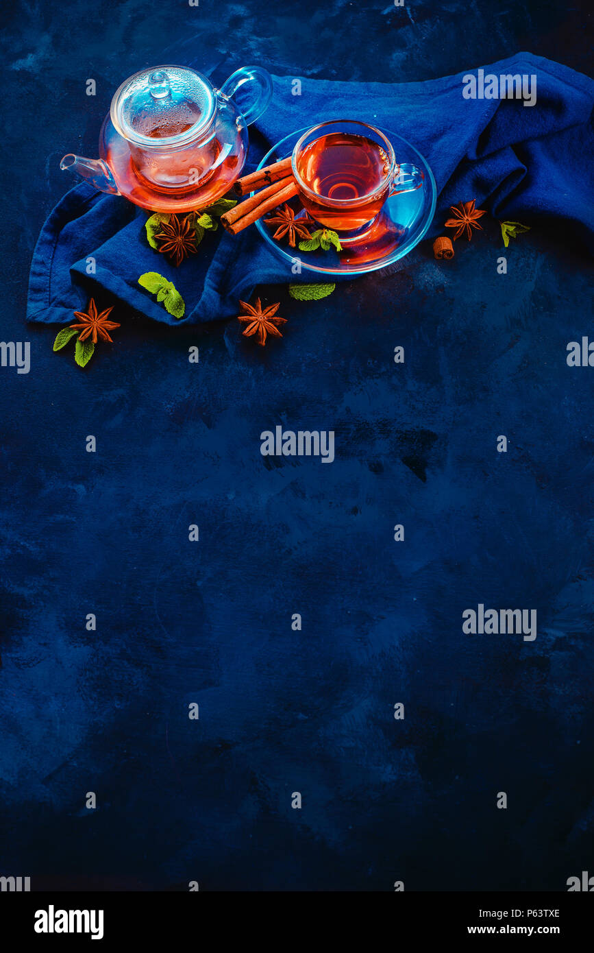 Tazza da tè e un minuscolo teiera con le fette di limone e foglie di menta su uno sfondo scuro. Colori vibranti bevanda calda ancora in vita con copia spazio. Tea time lay piatto Foto Stock