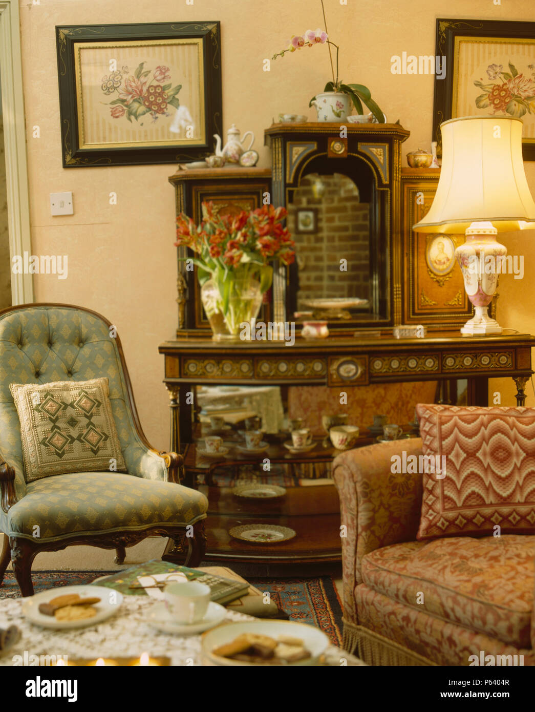 Vittoriano imbottiti sedia accanto al tavolo antico con la lampada accesa in cottage soggiorno Foto Stock