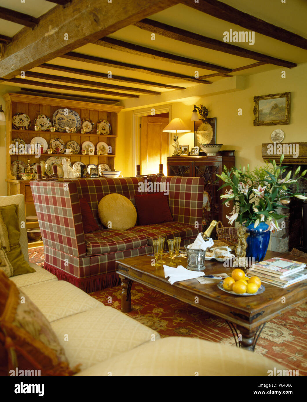 Cottage la stanza di seduta con red plaid Knole divano accanto a stile Indonesiano tavolino Foto Stock