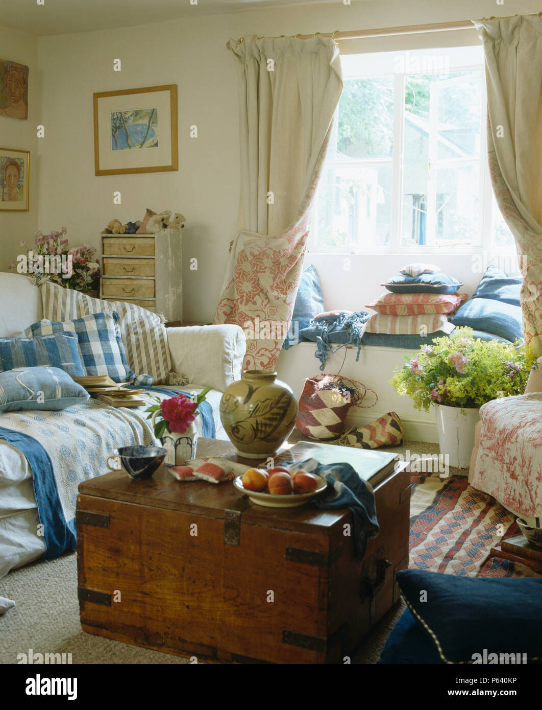 Antica cassa di legno in cottage la stanza di seduta con il blu+white plaid e cuscini sui divani color crema Foto Stock