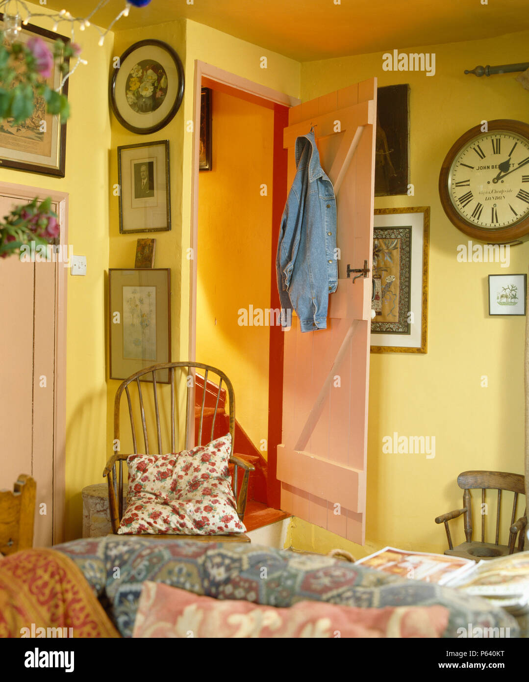 Orologio vintage e immagini su pareti di giallo economia cottage in stile salotto con pini porta Foto Stock