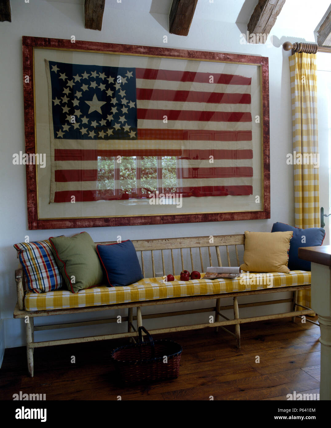 Incorniciato bandiera degli Stati Uniti d'America al di sopra di un vintage sedimentare in legno con giallo controllato cuscini in una florida la stanza di seduta Foto Stock