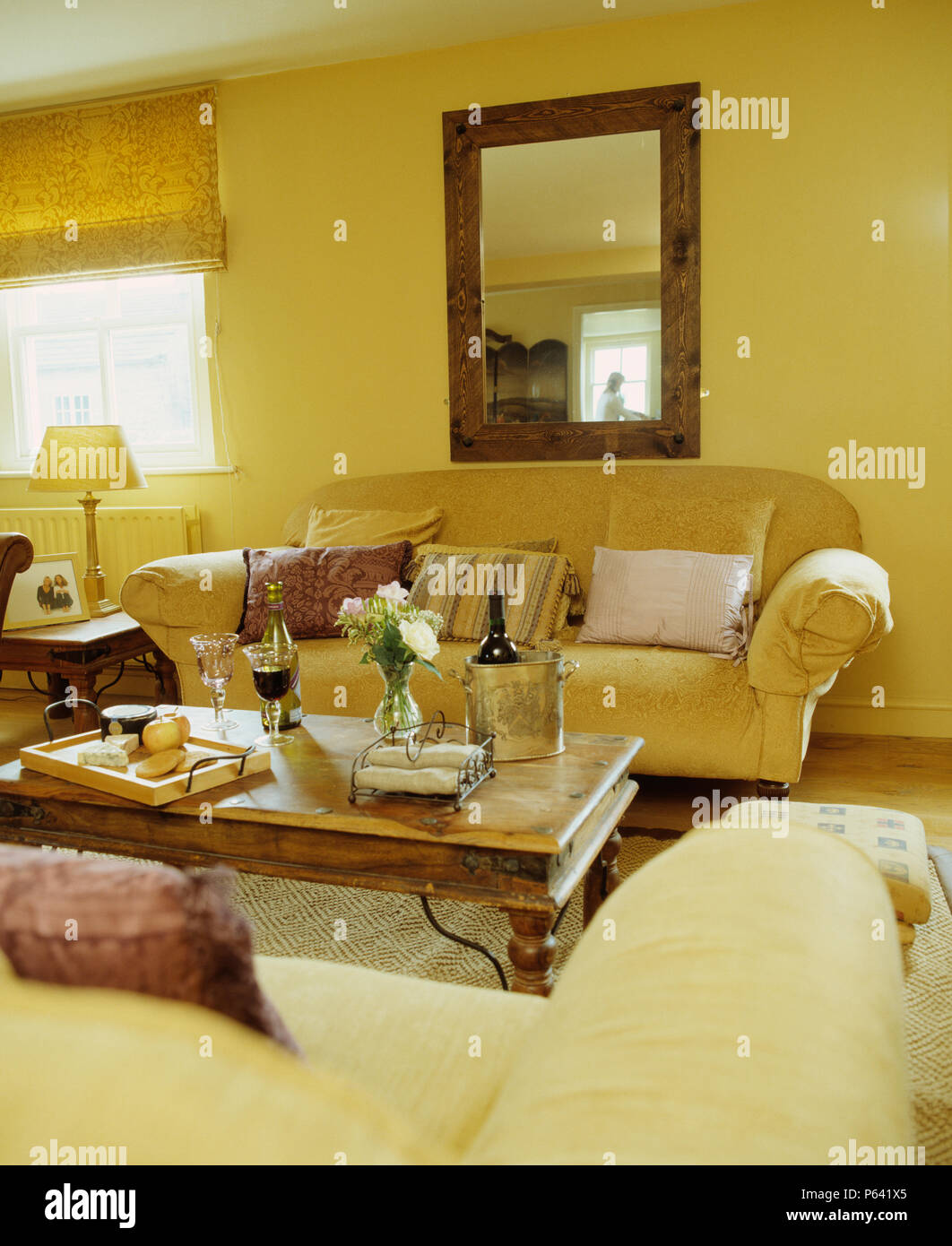Grande specchio sopra la crema divano in giallo country living room con un  stile Indonesiano tavolino Foto stock - Alamy