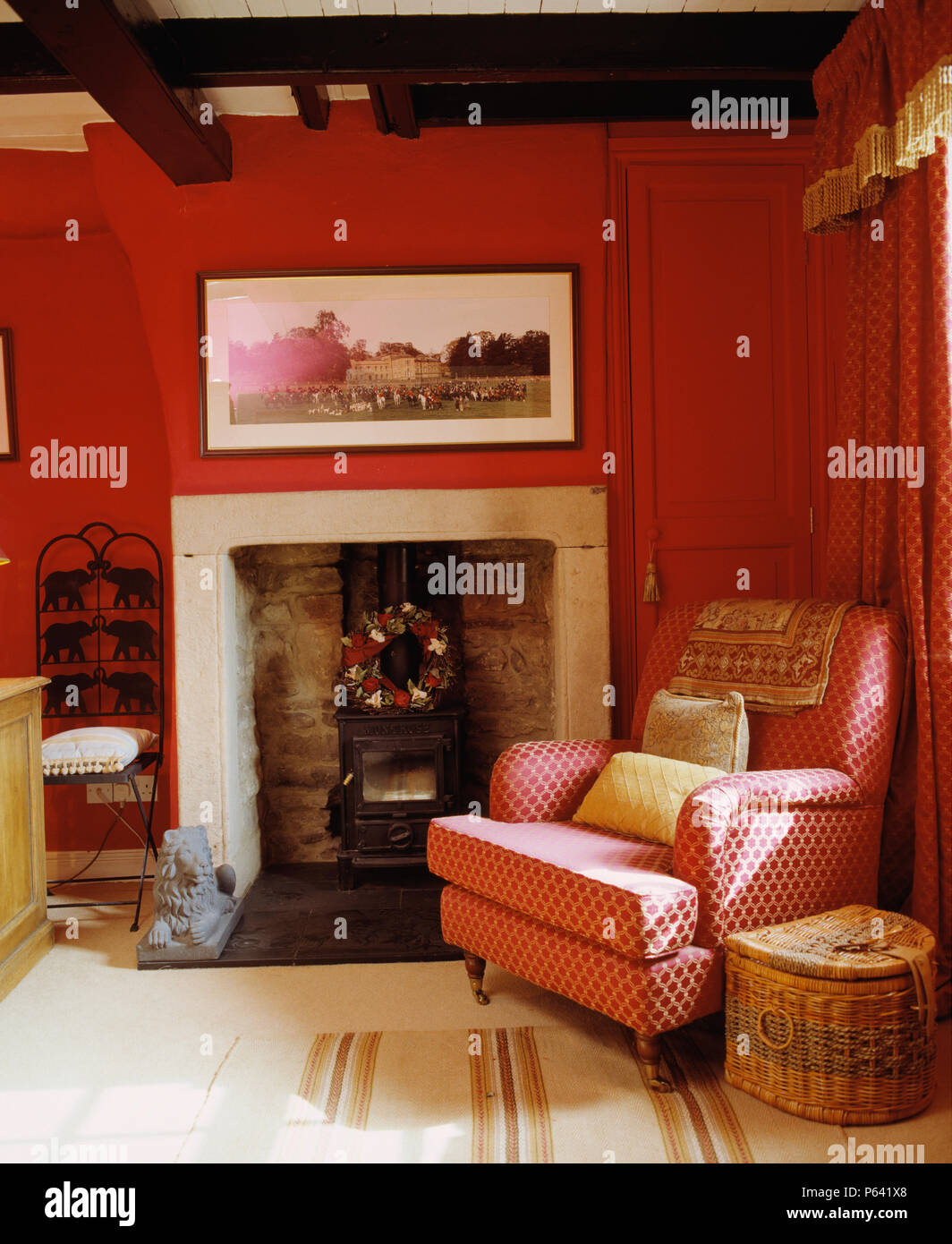 Modellato poltrona rossa accanto alla stufa a camino in rosso tradizionale salotto Foto Stock