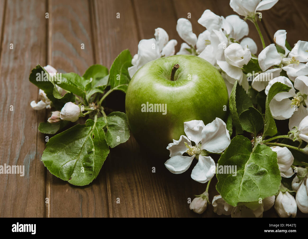 Mela Verde con fiori sul tavolo di legno Foto Stock