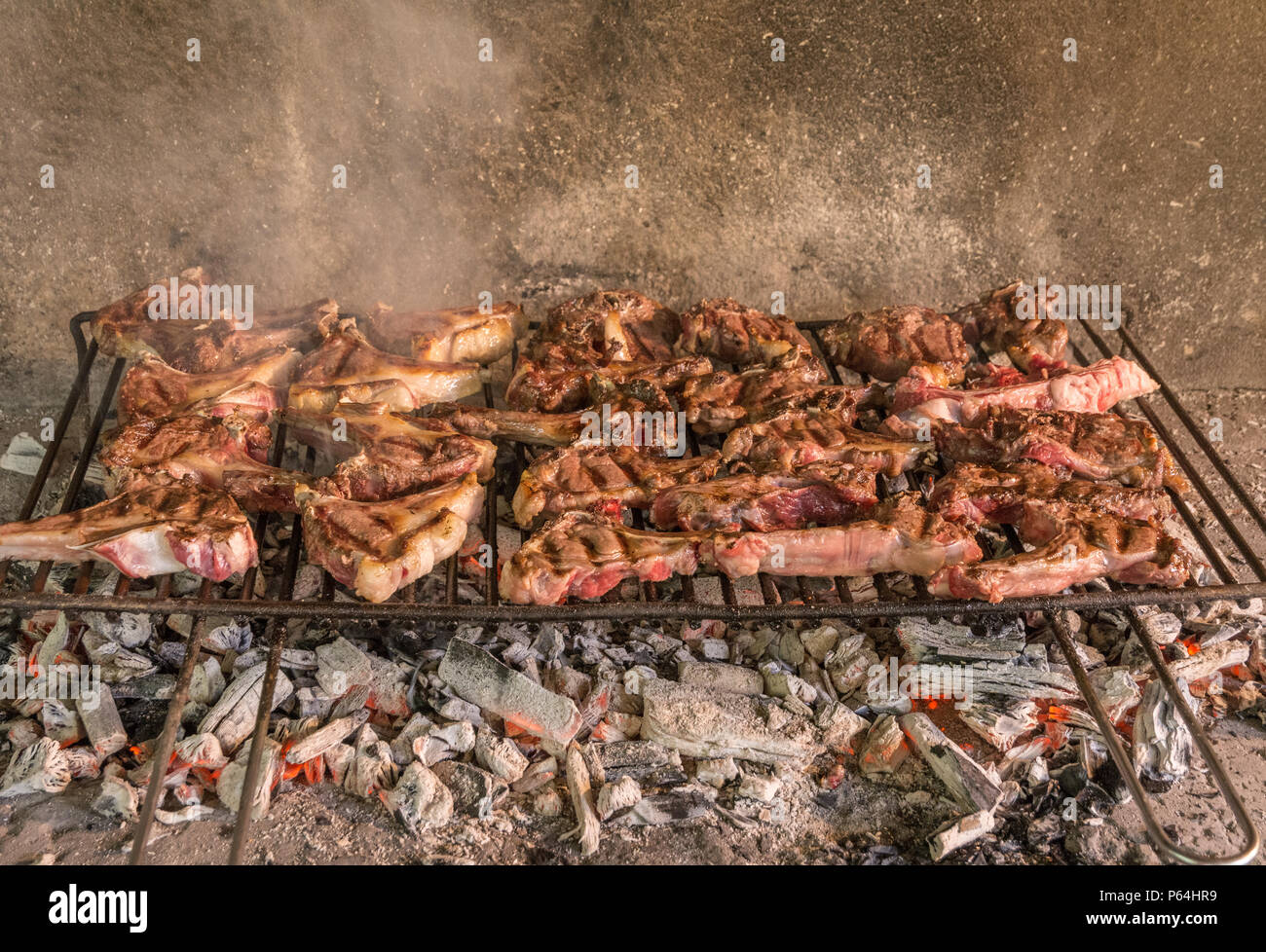 Grigliata di costolette di capra. Arrosto di carne su un barbecue in mattoni tipica barbecue in Sardegna, Italia. Messa a fuoco selettiva Foto Stock