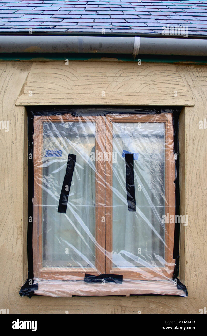 Fogli di plastica per mascherare latifoglie nuove finestre a battente mentre un cottage sotto lavori di rinnovo è reso, REGNO UNITO Foto Stock