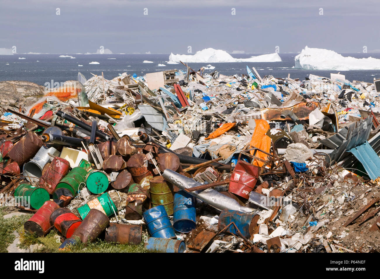 Rifiuti oggetto di dumping nella tundra al di fuori di Illulissat in Groenlandia con gli iceberg dietro dal Sermeq Kujullaq o Illulissat fiordo di ghiaccio. Il ghiaccio Illulissat Foto Stock