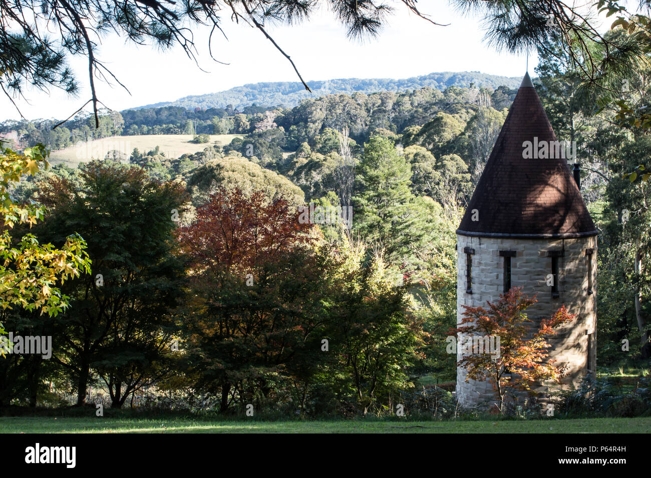Castello medievale torretta incastonato in un paesaggio giardino con alberi colline coperte in background Foto Stock