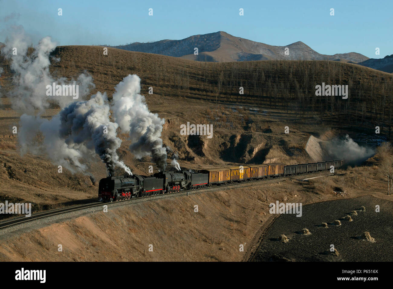 Un Holoku a nolo Daban guidato da due ex Cina Ferrovia QJ classe 2-10-2s fuoriesce dal numero di tunnel quattro sul Jing Peng passare la sezione della Ji- Foto Stock