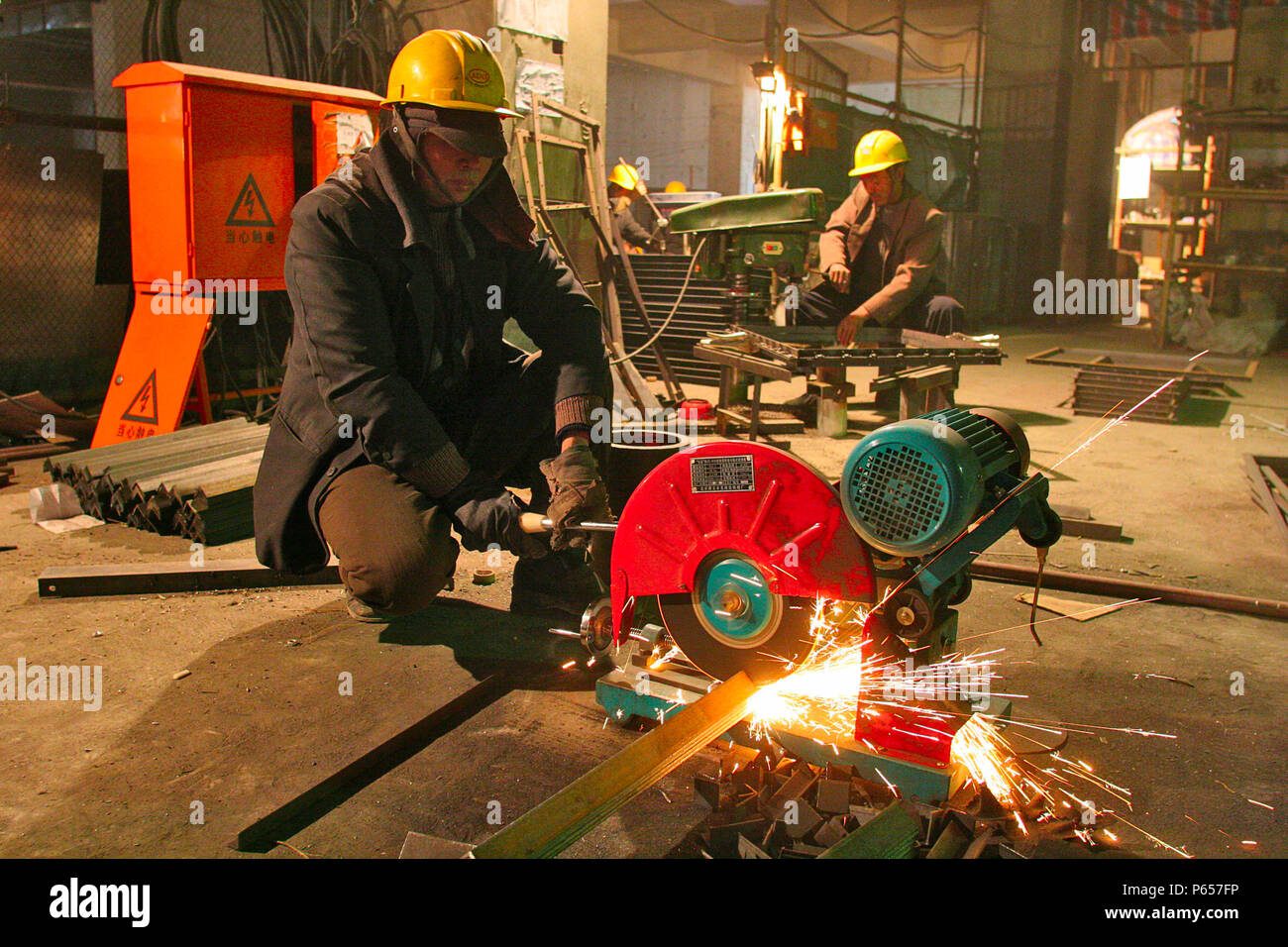 Un lavoratore cinese il taglio delle parti metalliche durante la costruzione dei condotti di condizionamento dell'aria in un nuovo ufficio in città centrale di Pechino. Foto Stock