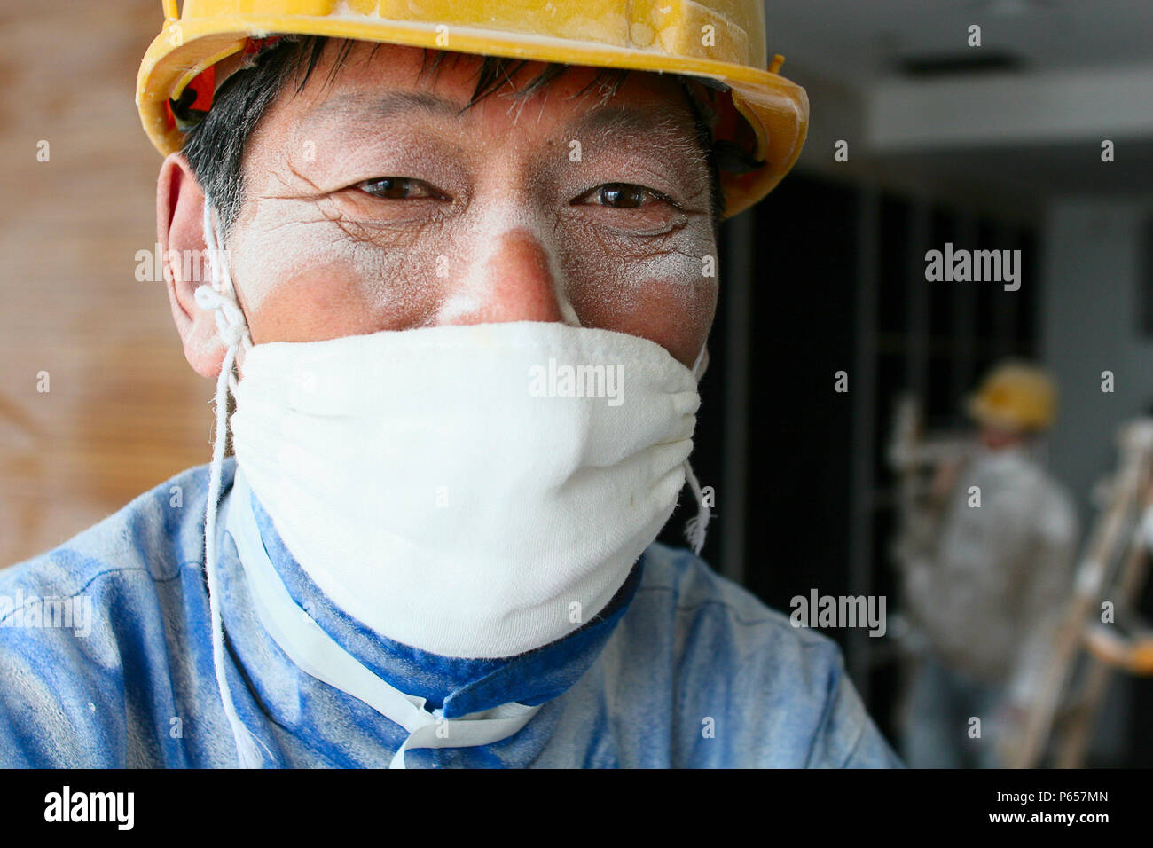 Un Lavoratore che indossa una maschera di cotone mette in pausa dal lavoro di levigatura intonaco del soffitto in una nuova torre di uffici a Pechino. Foto Stock