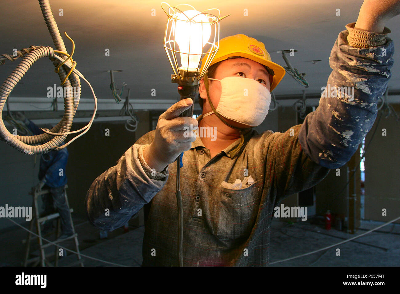 Un Lavoratore che indossa una maschera di cotone cablaggio test in una nuova torre di uffici a Pechino. Foto Stock