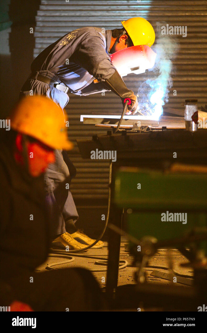 Lavoratori cinesi la costruzione di condotti di aria condizionata in un nuovo ufficio in città centrale di Pechino. Foto Stock