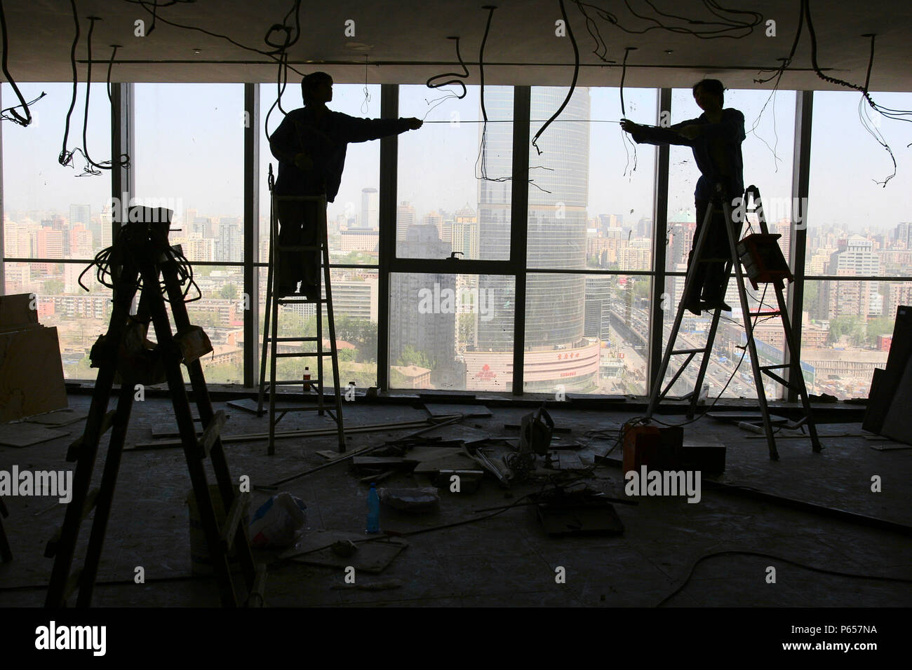 Lavoratori cinesi installare pannelli del soffitto in una nuova torre di uffici a Pechino. Foto Stock