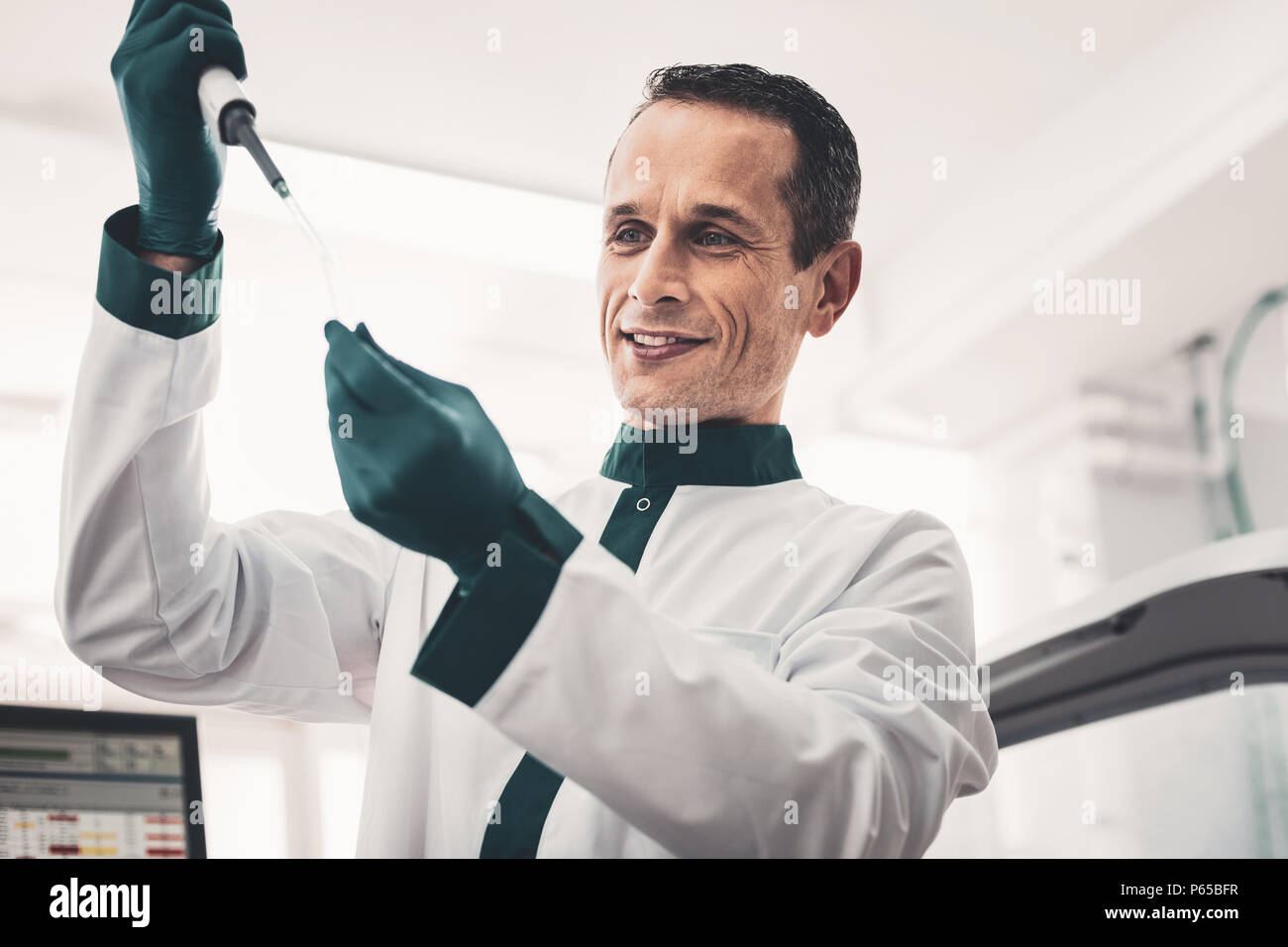Medico concentrato la caduta di un campione nel tubo di prova Foto Stock