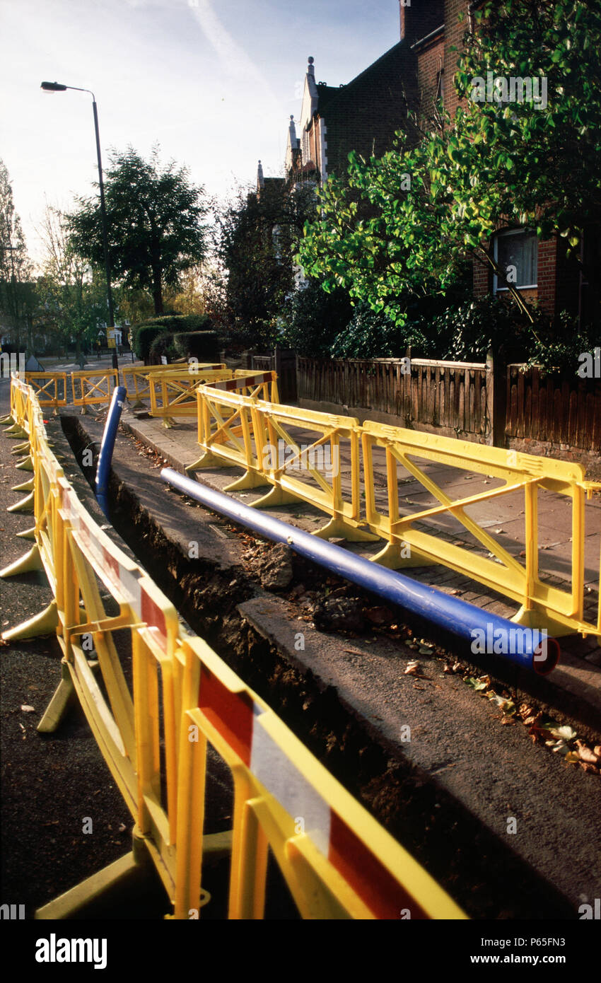 Plastica di sicurezza barriera attorno a una trincea per tubo di acqua in posa per collegamenti nazionali in Wandsworth, Londra, Regno Unito Foto Stock