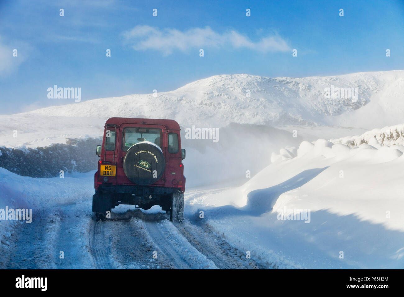 Un Landrover tenta di ottenere oltre il Kirkstone pass road sopra Windermere dopo che è stato bloccato dalla spindrift e soffiata dal vento, neve Lake District, UK. Foto Stock
