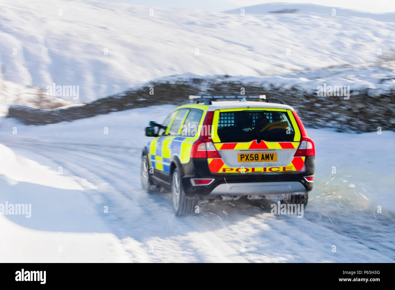 Una macchina della polizia tenta di ottenere oltre il Kirkstone pass road sopra Windermere dopo che è stato bloccato dalla spindrift e soffiata dal vento, neve Lake District, UK. Foto Stock