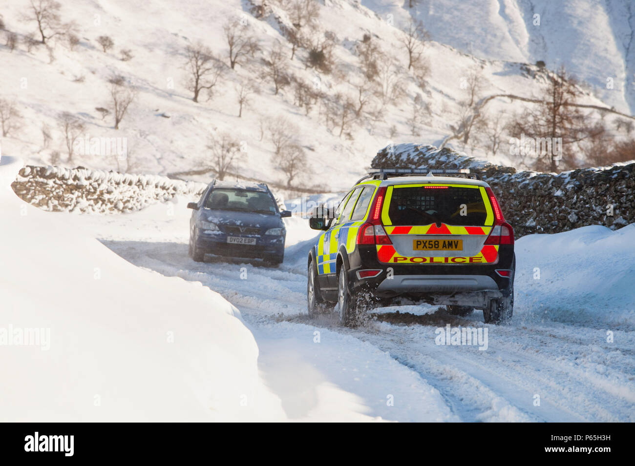 Una macchina della polizia tenta di ottenere oltre il Kirkstone pass road sopra Windermere dopo che è stato bloccato dalla spindrift e soffiata dal vento, neve Lake District, UK. Foto Stock