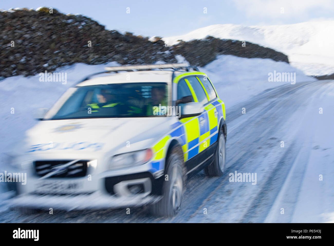 Una macchina della polizia tenta di ottenere oltre il Kirkstone pass road sopra Windermere dopo che è stato bloccato dalla spindrift e soffiata dal vento, neve Lake District, UK. Foto Stock