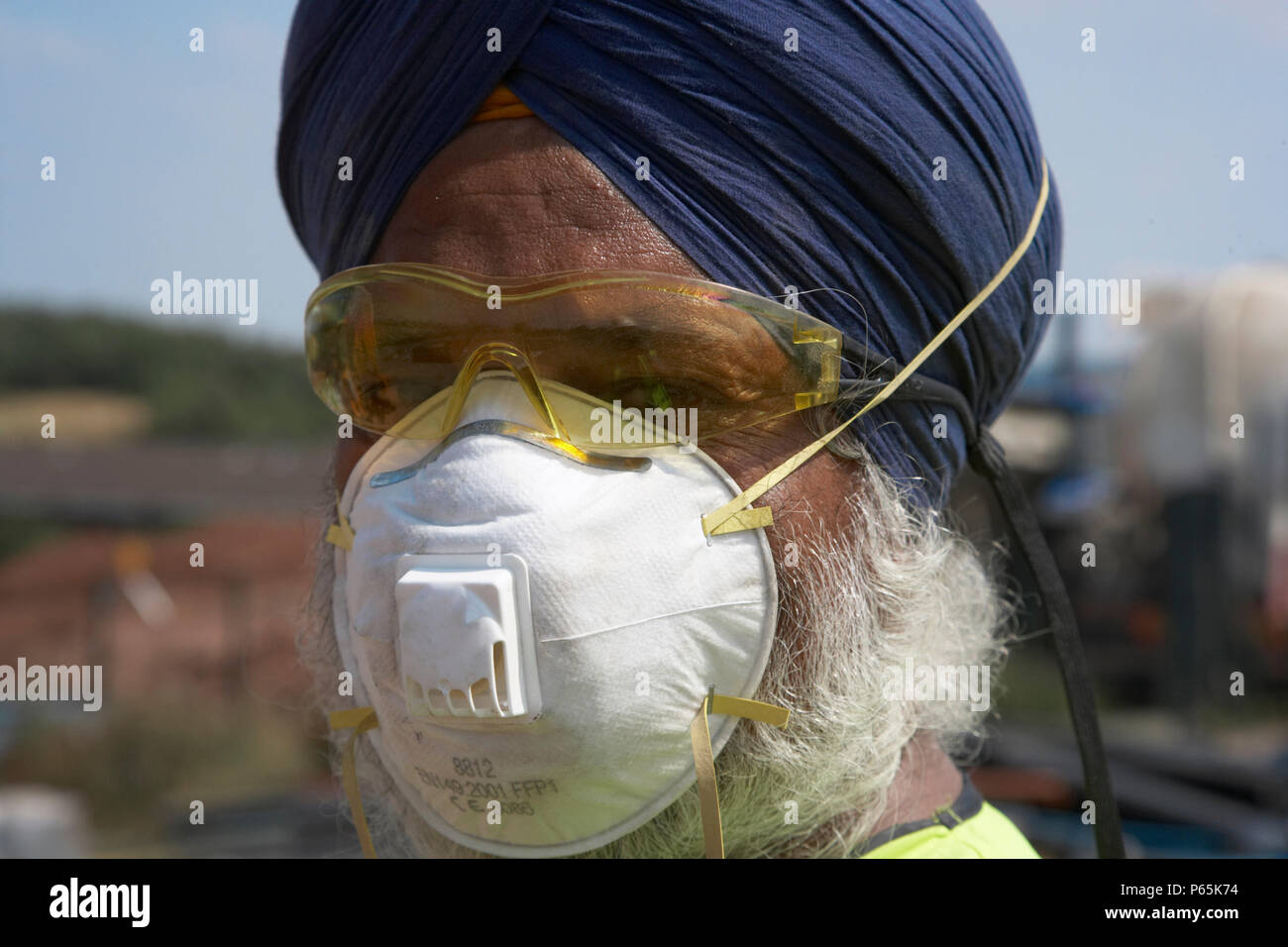 La religione sikh Lavoratore che indossa turbante e maschera di protezione e occhiali, UK. Lavoratori sikh sono autorizzati a non indossare il casco sul sito a causa di loro religiosa smentisce Foto Stock