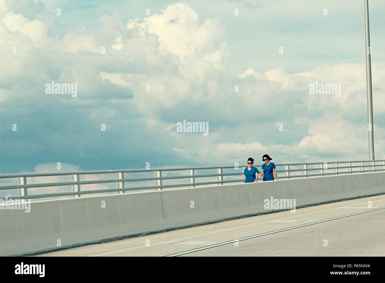 Due donne, entrambe in magliette blu, fare una passeggiata sul clearwater Memorial Causeway Foto Stock