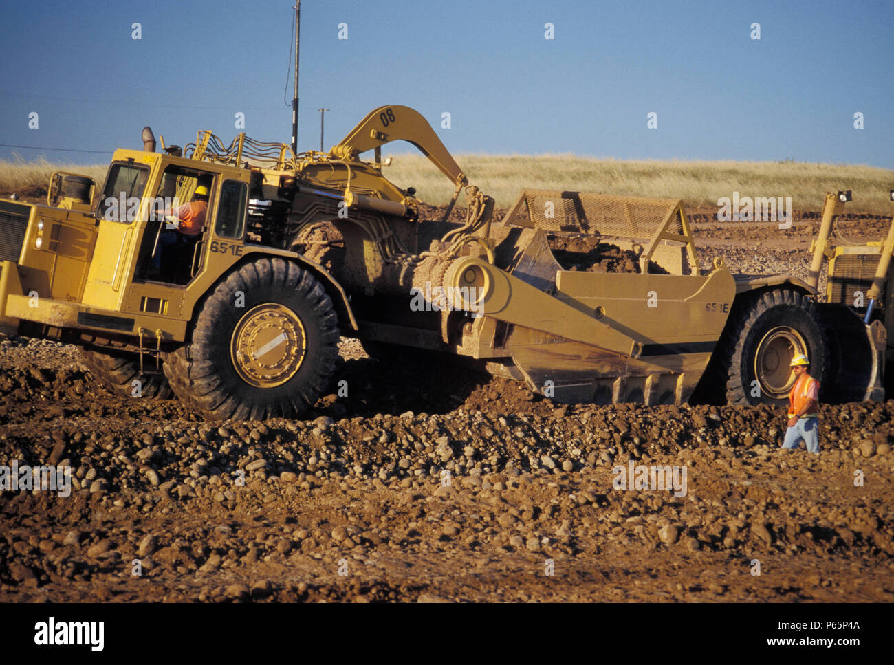 Caricamento del raschiatore sporco, foreman camminando in primo piano lo sviluppo residenziale, Lincoln, CALIFORNIA, STATI UNITI D'AMERICA Foto Stock