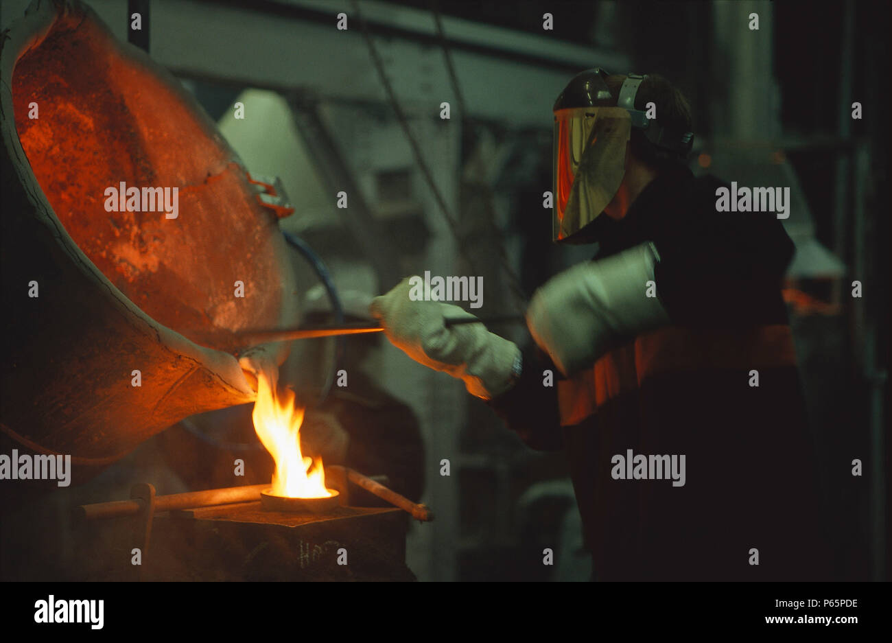 Lavoratore di acciaio in abbigliamento protettivo lavorare con forno. Foto Stock