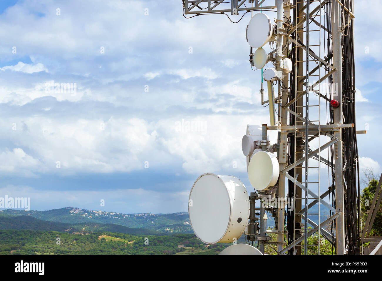 Torre di telecomunicazione con le antenne di comunicazione cellulari e sistemi radar. Contro il cielo nuvoloso sopra cime delle montagne verdi. Altezza di mountai Foto Stock