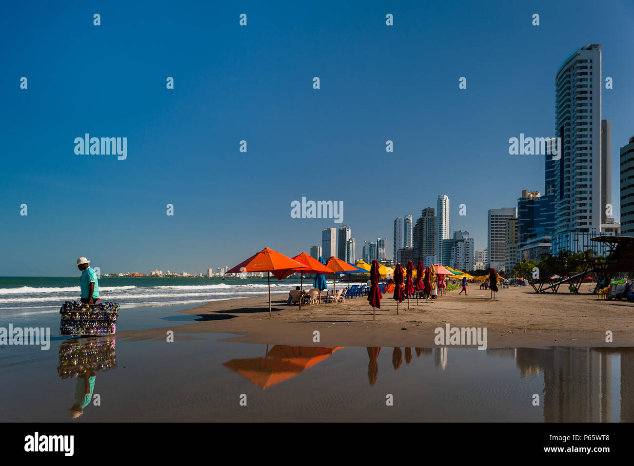 Un colombiano venditore ambulante passeggiate lungo gli ombrelloni sulla spiaggia di Bocagrande, una benestante quartiere di Cartagena, Colombia. Foto Stock