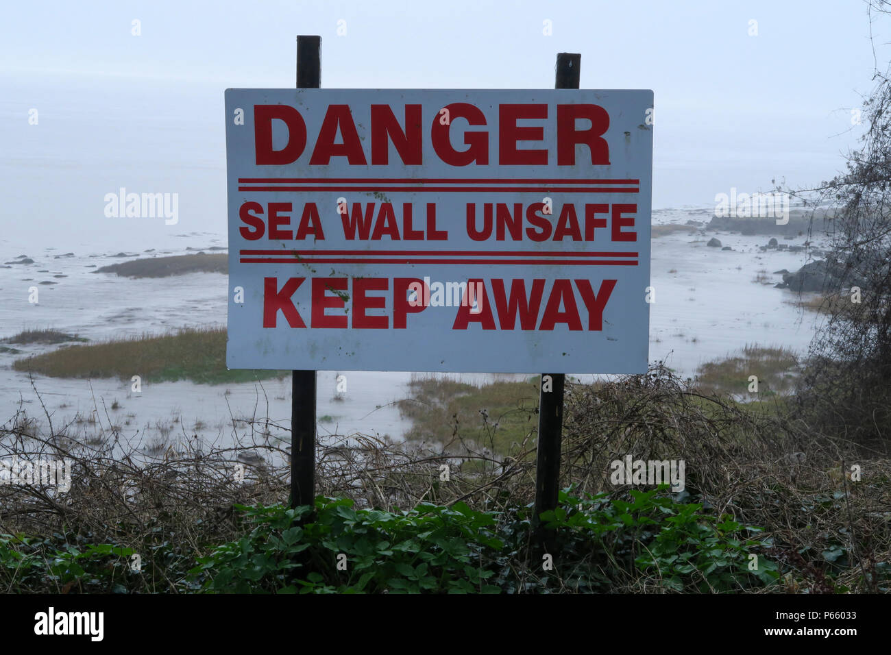 Severn Estuary, segnaletica di pericolo, Sea Wall insicura Foto Stock