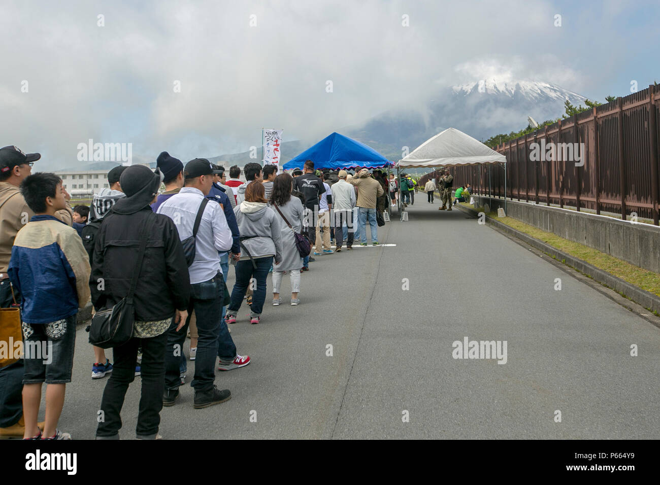 Giapponese residenti attendere in linea al di fuori della Fuji amicizia Festival il 7 Maggio a bordo di bracci combinato Training Center Fuji. Il festival comprende giochi e divertimento per tutte le età, come case di bounce, face painting e musica dal vivo da artisti locali e gli Stati Uniti 7 Banda della flotta's Orient Express. Il festival ha avuto anche numerose Visualizza sistemi di armi lungo con aeromobili e veicoli. Tra di loro vi erano i serbatoi di giapponese, UH60 Black Hawk e la MV-22B Osprey. Foto Stock