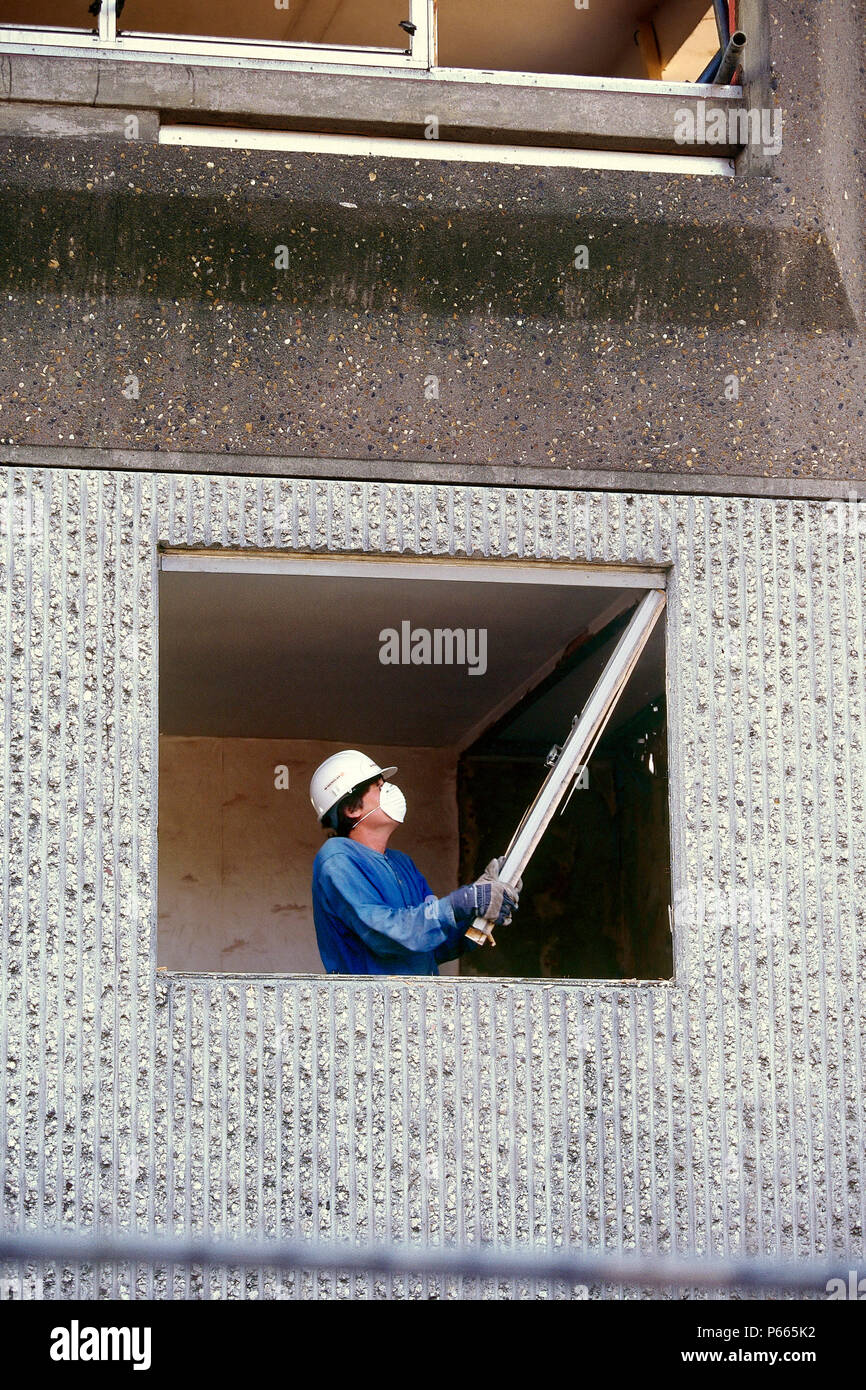 Operaio edile Demolizione di un telaio della finestra durante la rigenerazione di un consiglio in estate, Regno Unito. Foto Stock