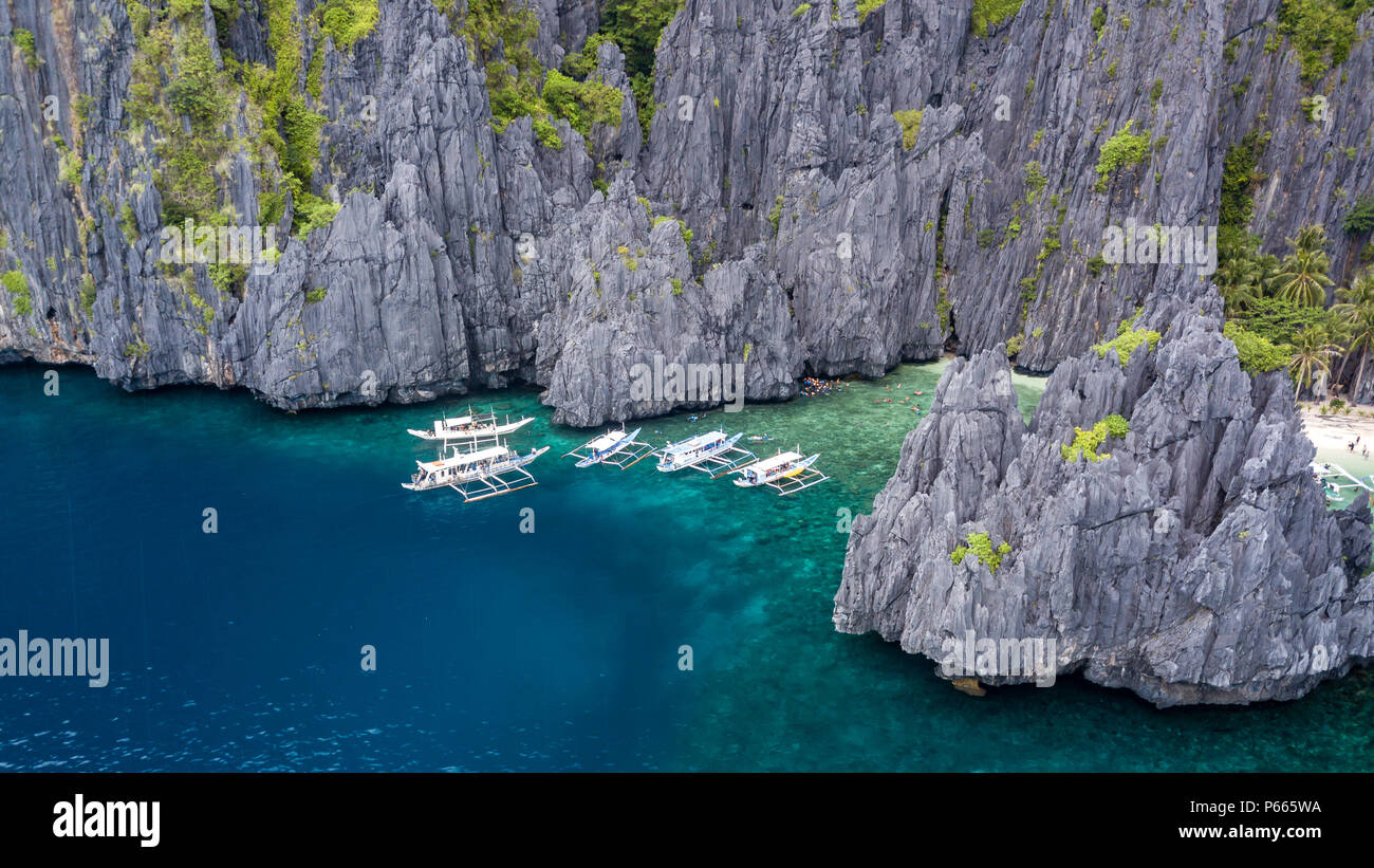 Antenna fuco vista delle barche tradizionali in una baia stretta con una bella spiaggia di sabbia e le torreggianti, frastagliate scogliere di calcare Foto Stock