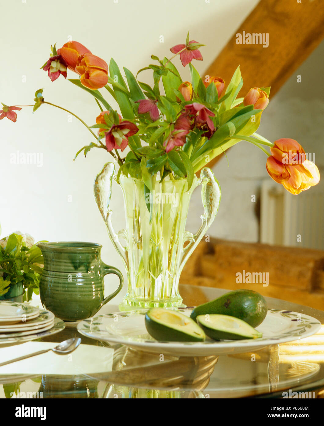 Still-Life di orange tulipani in vaso di vetro sul tavolo verde con caraffa in ceramica Foto Stock