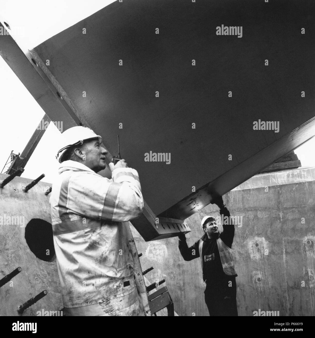 Posizionamento dei lavoratori prefabbricata in acciaio sul componente in situ in blocchi di cemento. Foto Stock