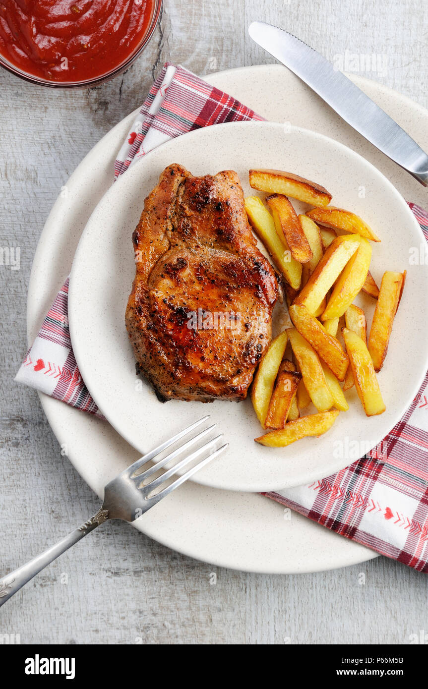 Succosa, rosolato bistecca di carne di maiale su un osso con patate fritte Foto Stock