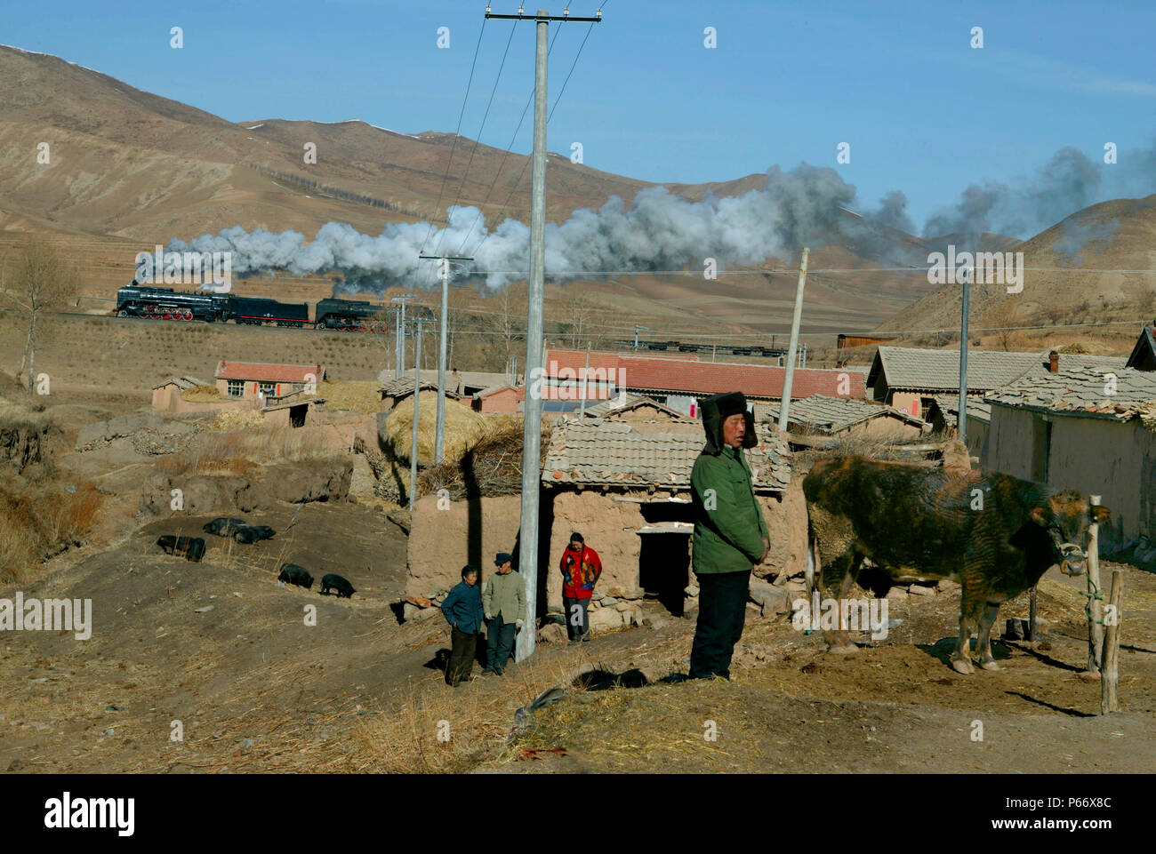 Un tipico villaggio di scena a Nandian sul Jing Peng pass, come merci trasportate da due ex Cina Ferrovia QJ 2-10-2s rende il suo assalto finale per la summi Foto Stock
