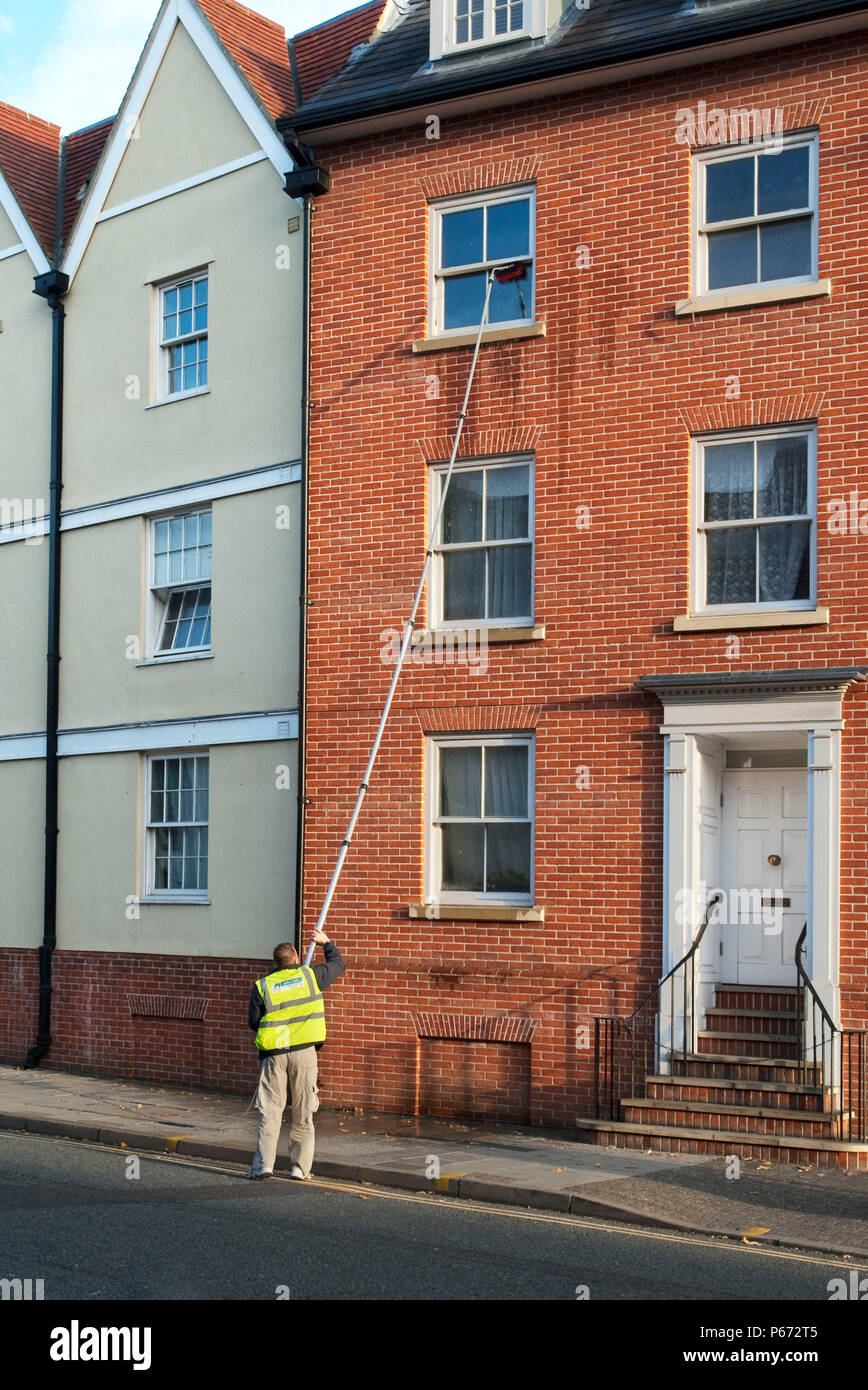 Un detergente per i vetri utilizzando una estensione acqua alimentata finestra spazzola di pulizia Ipswich Suffolk REGNO UNITO Foto Stock