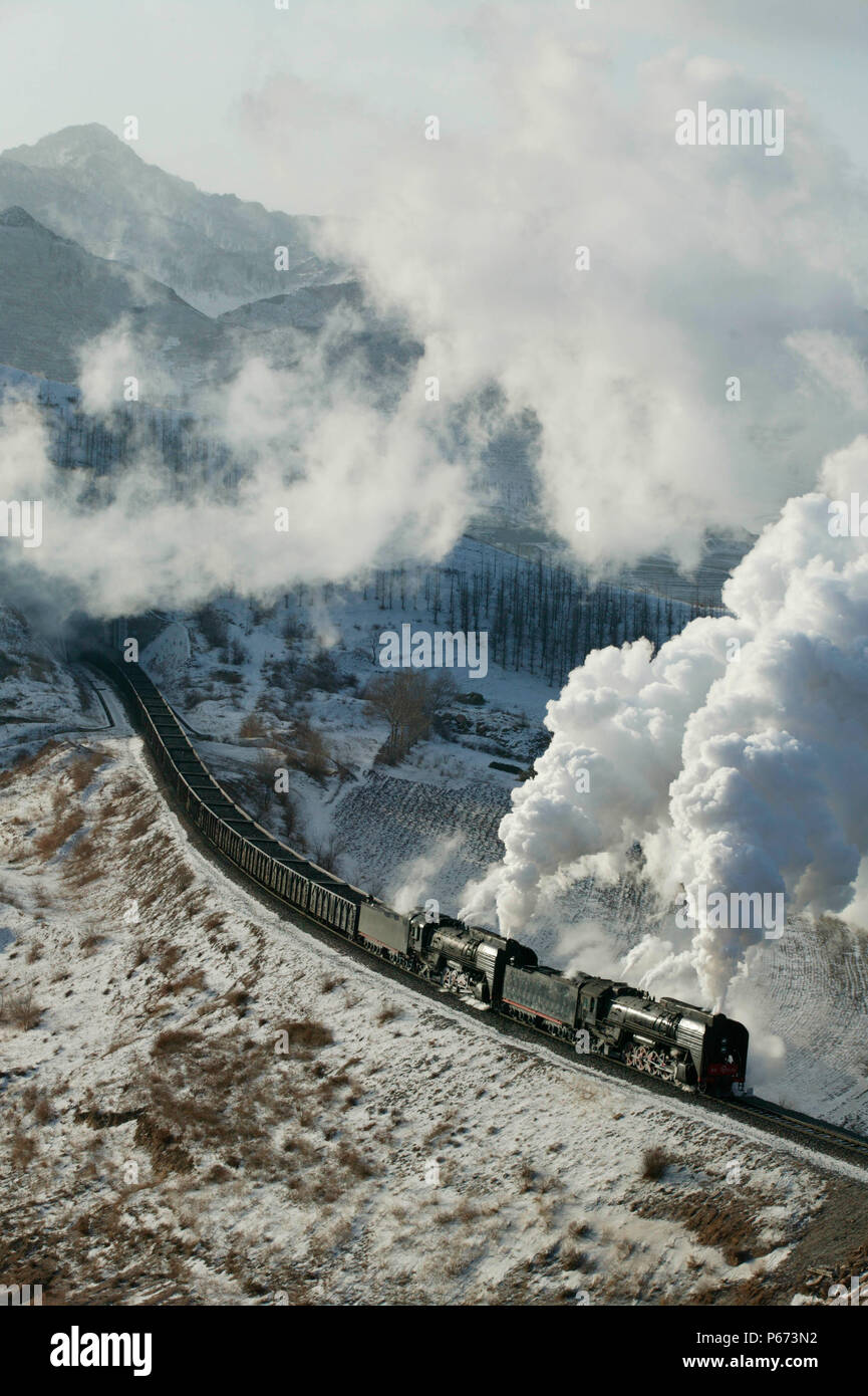 Un oriente legato di rake del carbone si svuota emerge dal numero di tunnel quattro dietro due QJ classe 2-10-2s sul Jing Peng sezione della ferrovia Ji-Tong in Inne Foto Stock