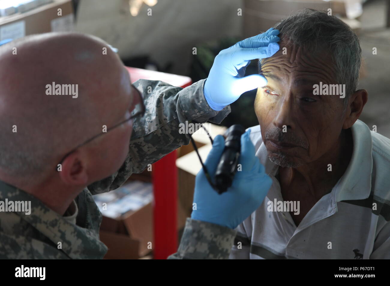 Stati Uniti Esercito Capt. Contrassegnare Dagenais, con la 410 Medical logistica aziendale, fornisce un dettagliato esame degli occhi di cittadini locali in optometria tenda durante una preparazione medica esercitazione a San Padro, Guatemala, 10 maggio 2016. Task Force il lupo rosso e l'esercito a sud conduce civile umanitario Assistenza Formazione per includere il livello tattico di progetti di costruzione e preparazione medica Esercizi di formazione fornendo accesso a medici e la costruzione di scuole in Guatemala con il governo del Guatemala e non-agenzie governative dal 05MAR16 a 18GIU16 al fine di migliorare la disponibilità di missione delle forze degli Stati Uniti e a p Foto Stock