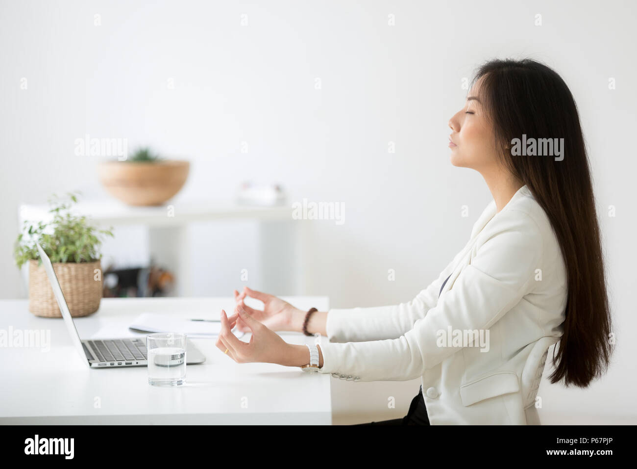 Calma dipendente asiatici meditando in office alleviare stress da lavoro Foto Stock