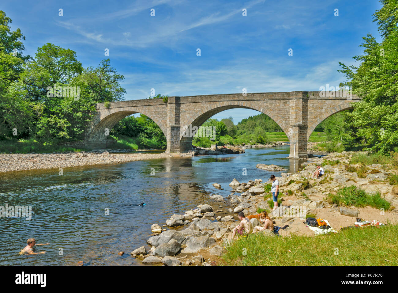 POTARCH ponte sopra il fiume Dee ABERDEENSHIRE una calda giornata d'estate con persone e cani e nuoto PICNICING sulla riva del fiume Foto Stock