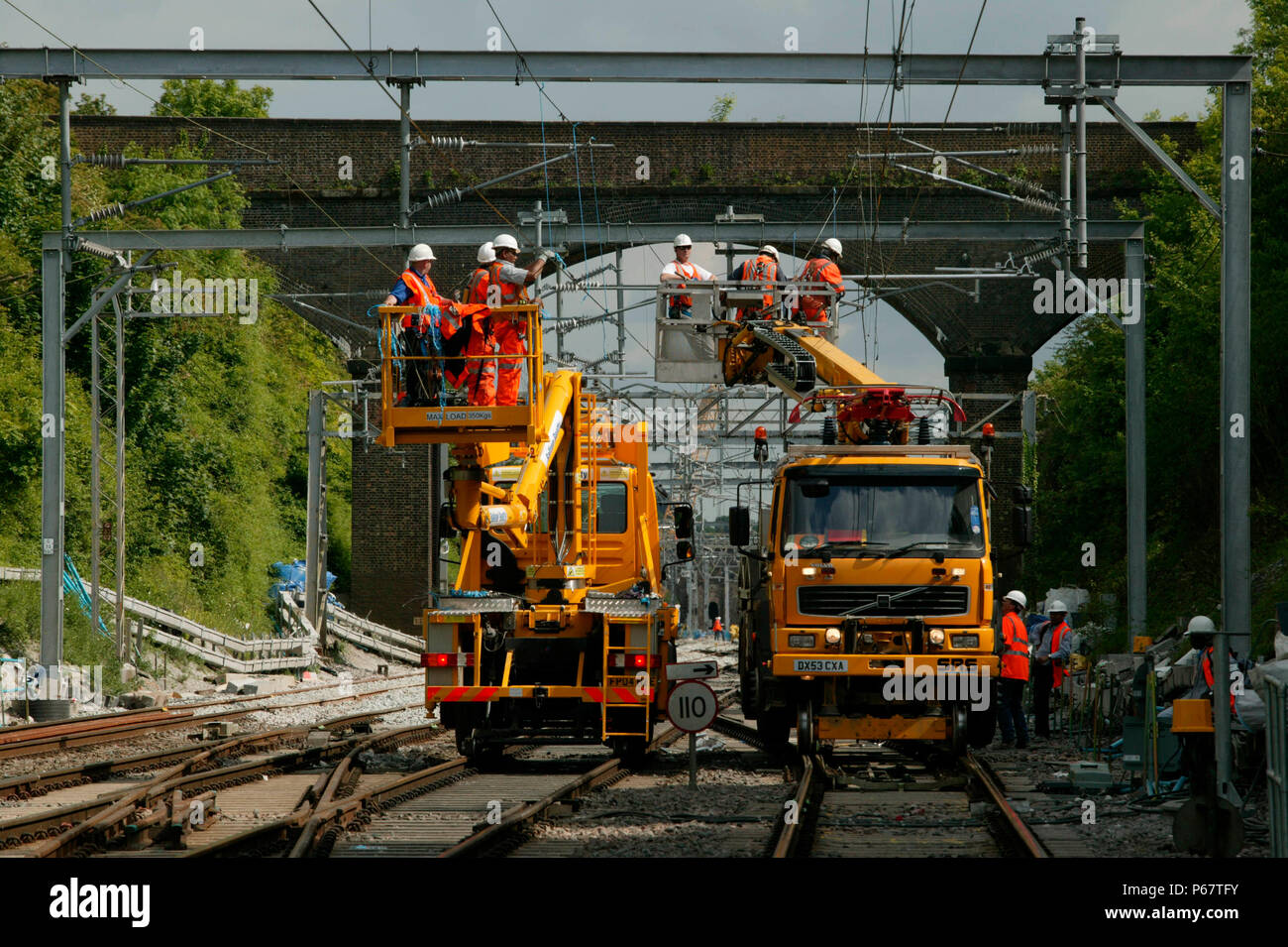 Impostare contro un tipico di Londra e North Western Railway overbridge due road-railers portare aereo di elettrificazione ingegneri presso l'ingresso meridionale t Foto Stock