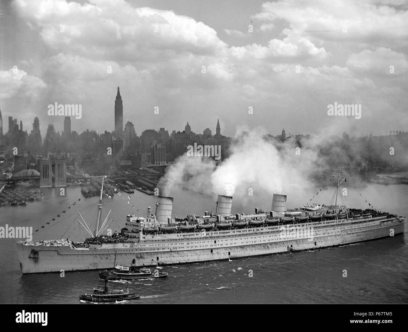 Fotografia del RMS Queen Mary che arrivano nel porto di New York con migliaia di soldati USA. Datata 1945 Foto Stock