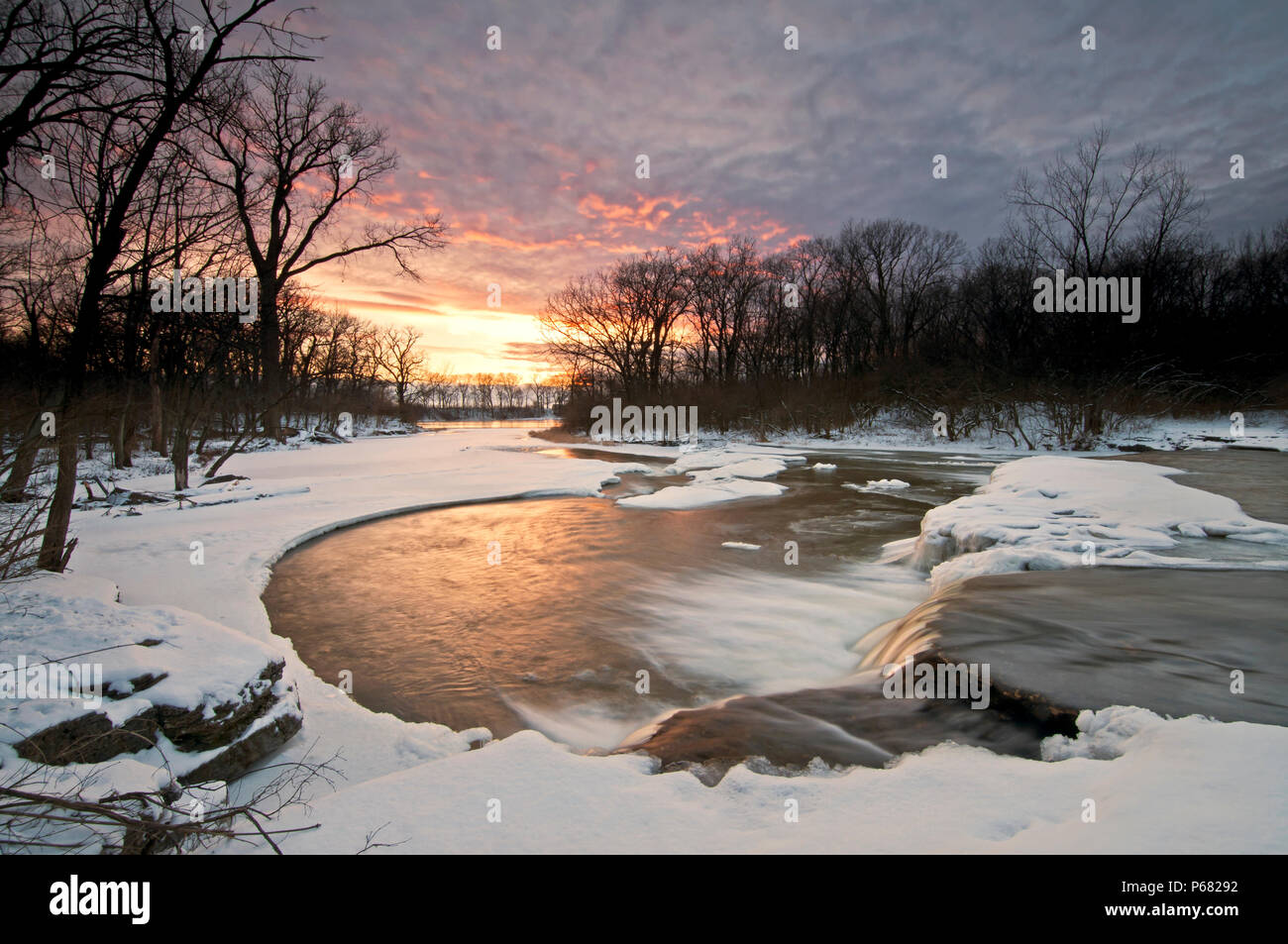 L'acqua gelida di Prairie Creek scorre su una cascata come il sole tramonta su un giorno d'inverno. Des Plaines Area di Conservazione, County, Illinois, Stati Uniti d'America. Foto Stock