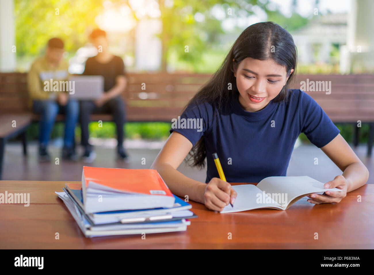 Studentessa prendendo appunti da un libro in biblioteca, giovane donna asiatica seduta a tavola facendo le assegnazioni nei college library Foto Stock