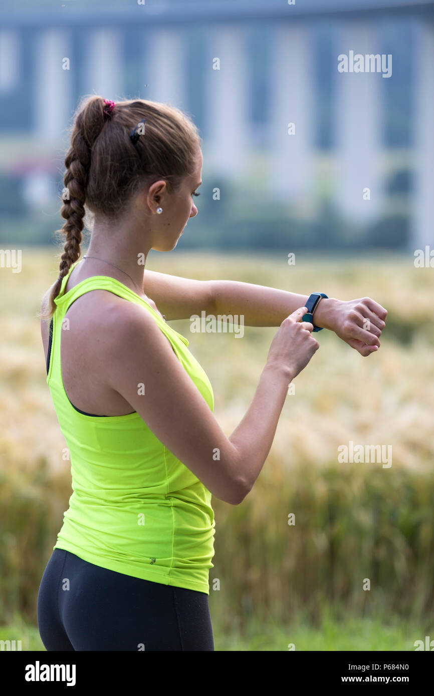 Giovane donna jogging, esecuzione, controllo i suoi segni vitali su un  orologio fitness, fitness tracker, frequenza cardiaca, il numero di passi,  distanza, tempo, calorie burn Foto stock - Alamy