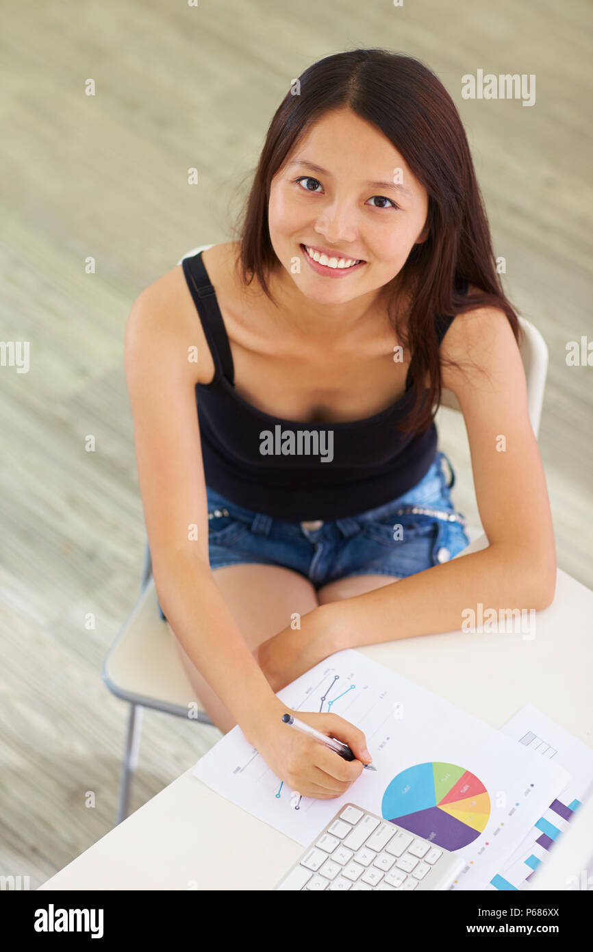 Una giovane donna cinese lavorando nell'ufficio a casa con il computer Foto Stock